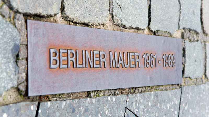 Tafel an einer Mauer auf der zu sehen ist, von wann bis wann Berlin durch die Mauer geteilt war.